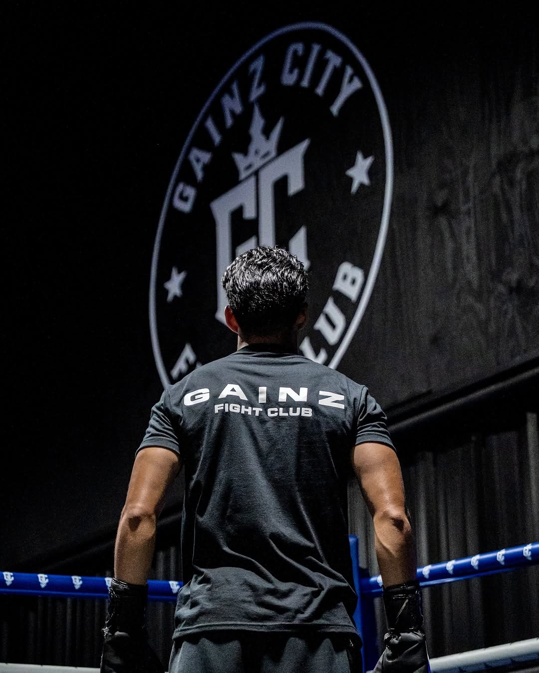 A fighter in the ring, seen from behind, wearing a Gainz Fight Club tee
